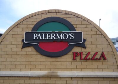 Outdoor logo on a brick half circle wall for Palermos Pizza.